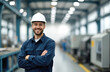 © Vadym - Smiling male engineer in work uniform, helmet stands at factory. Confident factory worker at industrial site, arms crossed. Foreman, technician in manufacturing, workplace, industrial job.