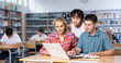 © JackF - Interested teenagers studying in information technology class at college library, sitting around one computer