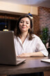 © DC Studio - Portrait of caucasian female executive seated at her desk with her laptop ready, preparing for a productive late night work session. Closeup of woman manager in office, smiling at camera.