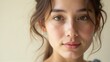 © Endry Creator - A woman with brown eyes and soft features gazes directly at the camera with a gentle expression, set against a light beige background. Generative, AI,