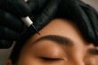 © Boke - Beautician applying permanent makeup on eyebrows using special device