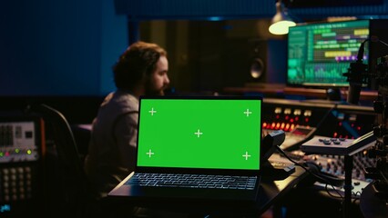 Leinwandbilder - Sound designer uses audio mixer and greenscreen layout in professional studio, adjusting volume levels while pressing buttons on desk. Control room equipped with technical recording gear. Camera B.