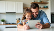 © schiers_images - A father and his young daughter happily using a digital tablet together in a cozy kitchen, emphasizing family technology interaction and creating loving childhood memories in a bright, modern setting