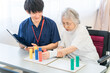 © buritora - 介護施設・リハビリ施設で働く作業療法士の職員とリハビリをするシニア女性