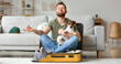 © Pixel-Shot - Young man with cute dog meditating in suitcase at home