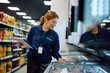 © Drazen - Female store manager inspecting food while working in refrigerated compartment at supermarket.