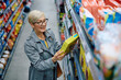 © Drazen - Happy senior woman  reading label on cereal box while buying at supermarket.