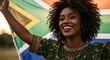 © Firman Dasmir - Smiling woman proudly displaying the South African flag outdoors