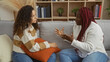 © Krakenimages.com - Two women friends sitting in a cozy living room engaged in a serious conversation, emphasizing their strong bond and emotional connection within a comfortable home setting.