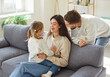 © Studio Romantic - Portrait of young happy family of three sitting on sofa at home with little cute child girl and smiling. Joyful parents enjoying spending time with daughter. Love, care and happy family concept.