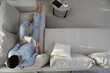 © New Africa - Man reading book on sofa in living room, above view