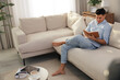 © New Africa - Man reading book on sofa in living room