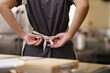 © ijeab - Close up of a young chef tying apron before preparing a meal in a commercial kitchen setting.