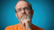 © Radianshots - Thoughtful man in orange shirt pondering a question against a blue background