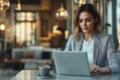© yasto - Focused Young Woman Working on Laptop in a Cozy Cafe