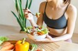 © Emmy Ljs - Sporty woman eating healthy salad. Healthy food ideas that are beneficial such as superfoods, clean eating, vegetarianism, and weight loss diets.