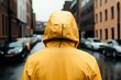 © Olga - Hooded figure in yellow raincoat on a rainy urban street