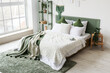© Pixel-Shot - Modern bed with green plaid and shelving unit in interior of bedroom