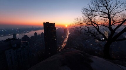 Aufkleber - Cityscape at sunset with buildings roads and river silhouetted against the colorful sky. The view includes a tree on the right and orange horizon