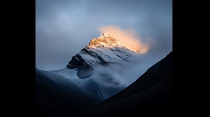 Aufkleber - A majestic snow-capped mountain peak illuminated by golden sunlight emerging from a sea of clouds. Dark, sloping hills frame the dramatic vista with a moody atmosphere