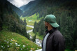© Sumit - Man standing at a mountain viewpoint overlooking a lush green valley and winding river, enjoying the serenity of nature.
