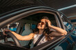 © Nataliya - Happy and excited woman sitting in the car on a day trip in the summer, wearing sunglasses. Travel adventure drive, happy summer vacation concept