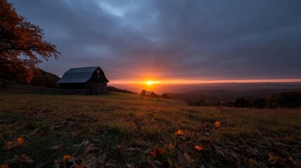 Leinwandbilder - Dramatic sunset over a rustic structure on a hillside showcasing warm orange hues against a dusky blue sky with scattered clouds and fall foliage