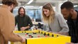 © Marin Studio - Team Building Fun: Colleagues enjoying a foosball game in a bright and modern office, fostering camaraderie and relaxation during work hours.