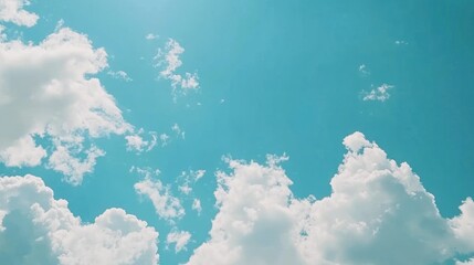 Wall Mural - White fluffy clouds floating across a clear blue sky