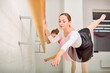 © TRAVELARIUM - Two young female ballerinas practice at ballet barre. One has brown hair, other partially visible. Soft lighting in airy studio enhances their graceful movements