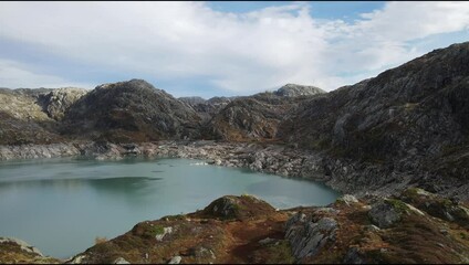 Wall Mural - Drone scenery of a serene lake with rugged surroundings on a sunny day with white clouds in Norway