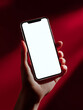 © Andsx - Elegant Hand Holding Smartphone with Blank Screen Against a Dramatic Red Background