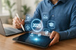 © Urelzita - Futuristic business concept showing 2025 digital strategy with AI, education, analytics and sustainability icons on a transparent screen tablet interface..