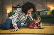 © Miljan Živković - Mother and daughter use digital tablet to watch online video at home