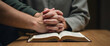 © HaJung - Christian group holds hands and prays together with Bible on wooden table representing devotional prayer meetings and collective worship. concept as Christian group holds hands and prays together with