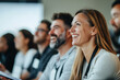 © Varitnan - Happy young woman smiling at business seminar with diverse audience