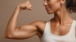 © aciddreamStudio - Woman demonstrating strength by flexing her arm muscle against a light beige background