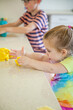 © Austockphoto - Young kids playing with playdough on the kitchen bench