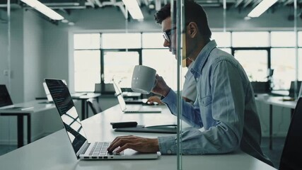 Aufkleber - Professional developer focusing on project deadline while drinking coffee, working efficiently at organized desk with laptop in bright, modern office environment
