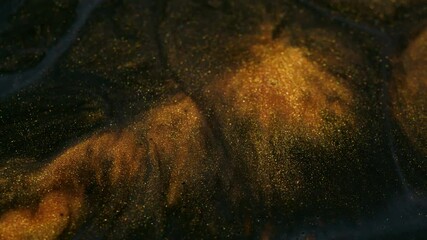 Wall Mural - Glitter fluid. Shimmering spill. Golden powder particles paint emerge swirl flowing in black gray gel emulsion art abstract background.
