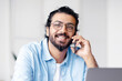 © Prostock-studio - Cheerful Indian Freelancer Guy Drinking Coffee And Talking On Cellphone While Having Break During Work With Laptop Computer At Home Office, Speaking With Friends, Resting At Workplace, Free Space