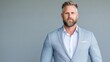 © PACESTOCK - A professional businessman in light grey suit standing confidently against a plain grey background, close-up portrait with short beard, and corporate headshot.