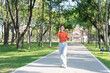 © Thitisak - Asian woman walks and listens to music in a public park.