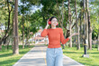 © Thitisak - Asian woman walks and listens to music in a public park.