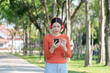 © Thitisak - Asian woman walks and listens to music in a public park.