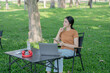 © Thitisak - Asian woman sitting using laptop, working in a park