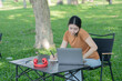 © Thitisak - Asian woman sitting using laptop, working in a park