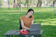 © Thitisak - Asian woman sitting using laptop, working in a park