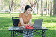 © Thitisak - Asian woman sitting using laptop, working in a park