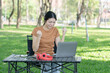 © Thitisak - Asian woman sitting using laptop, working in a park